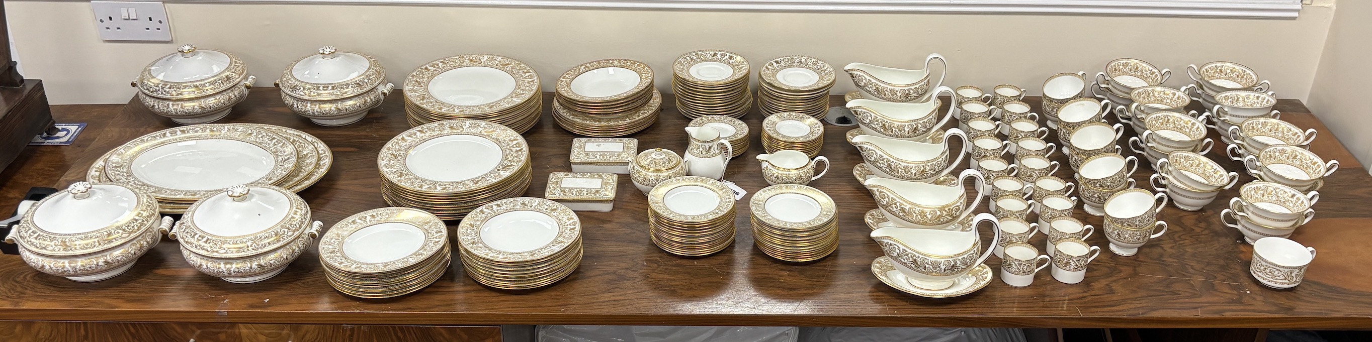 An extensive Wedgwood Gold Florentine dinner service, including 26 dinner plates, 50 side plates, 18 soup bowls with 16 saucers, 6 tea cups and 4 saucers, 6 bowls, 6 large cheese plates, 5 gravy boats and 3 saucers, 3 ve